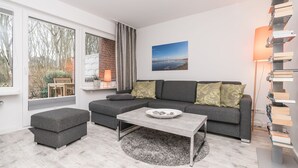 Un salon moderne avec un canapé gris, une table basse et une bibliothèque.