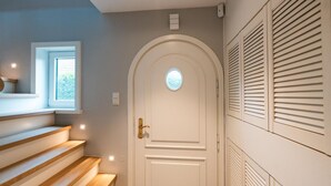 A white door with a small window, wooden stairs, and a wall with shutters. - Strandhütte - House Strandhütte (Sylt)