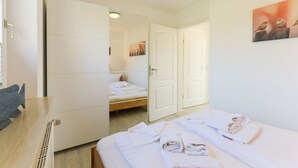 A hotel room with a bed, a desk, a chair, and a painting on the wall.