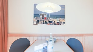 A dining area with a table, chairs, a bottle of water, and a menu. - Greenlön - House Tilly - Greenlön (Sylt)