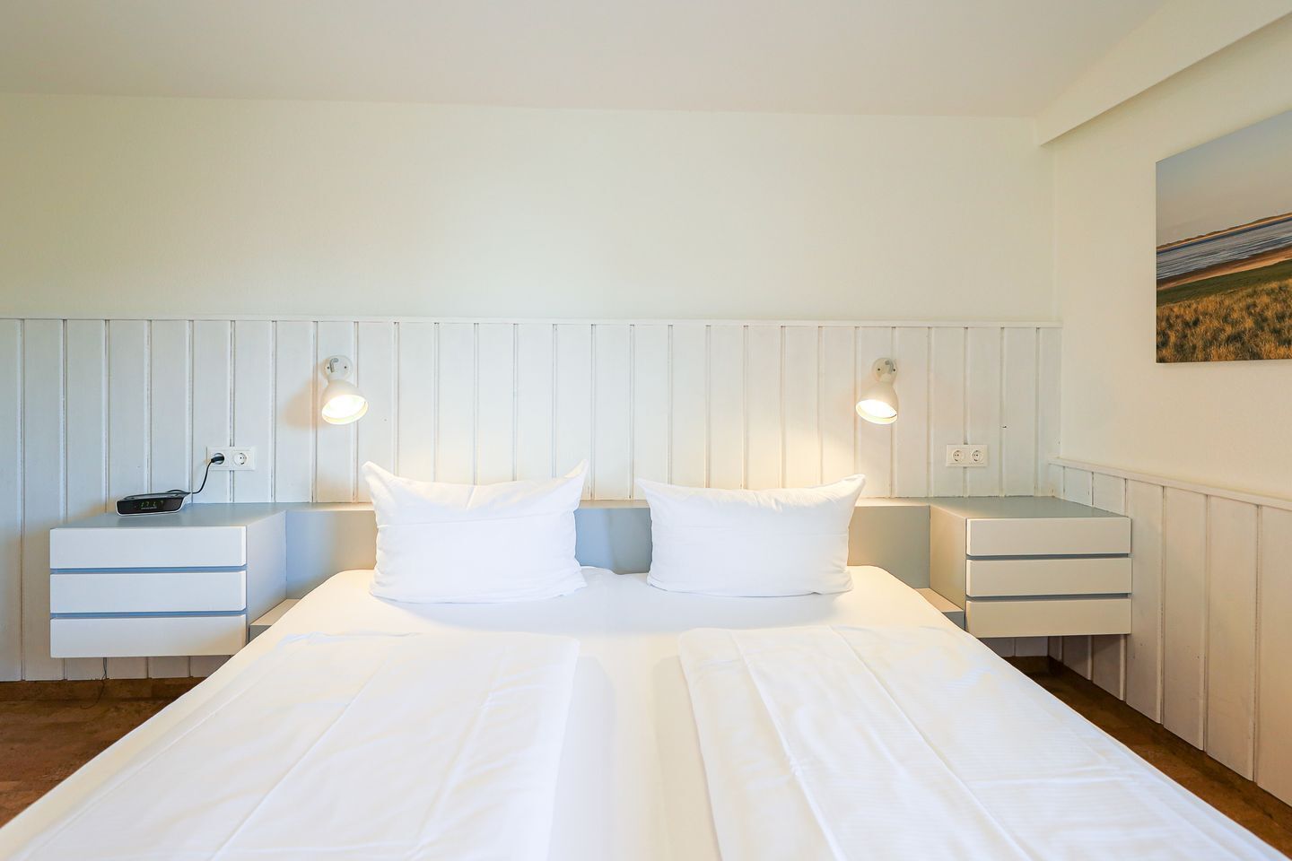 Ett hotellrum med en stor säng, två sängbord och en väggmonterad lampa.