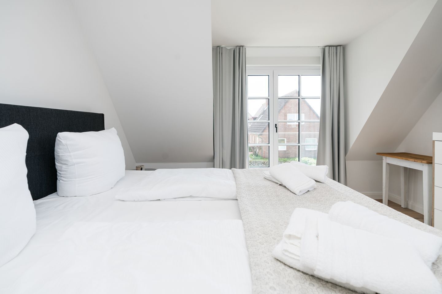 Una habitación de hotel moderna con una cama grande, un escritorio y una ventana con cortinas.