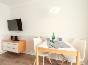 A modern room with a wooden desk, a flat-screen TV, and a dining table with chairs. - Klööwer - House Ilse - Klööwer (Sylt)