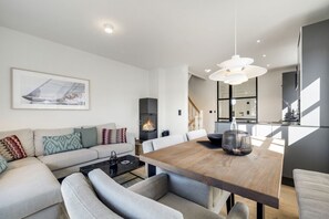 A modern living room with a fireplace, a dining area, and a staircase leading to another level.