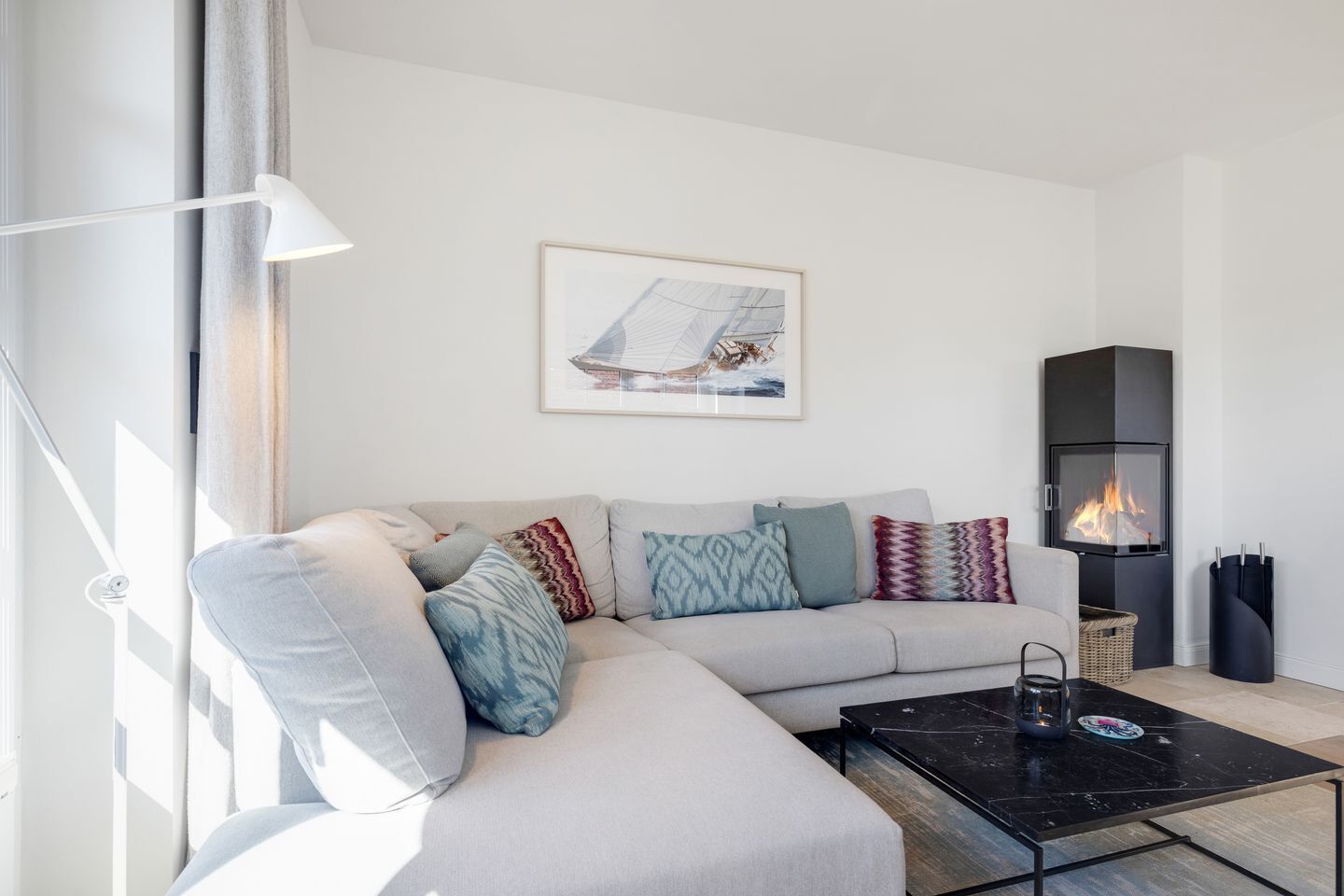 A modern living room with a sofa, a coffee table, a fireplace, and a framed picture on the wall.