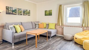 A modern living room with a grey sofa, wooden coffee table, and a yellow bean bag. - Imke - House Rolf - Imke (Sylt)