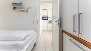Hotellihuone, jossa on sänky, pieni keittiönurkkaus ja kylpyhuone, jotka näkyvät avoimesta ovesta.