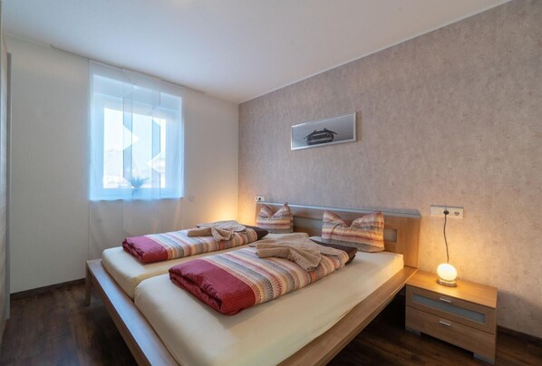 A bedroom with a bed, bedside tables, a window, and a wall-mounted picture.