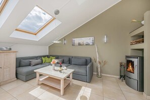 A modern living room with a skylight, grey sofa, coffee table, fireplace, and a cabinet.