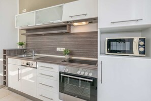 A modern kitchen with a built-in microwave, stainless steel appliances, and a backsplash.