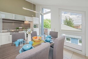 Ett modernt kök med matplats, stora fönster och utsikt över omgivningen.