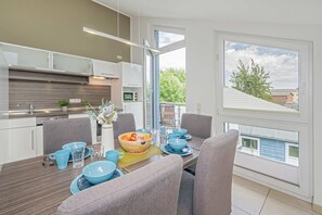 Ett modernt kök med matplats, stora fönster och utsikt över omgivningen.