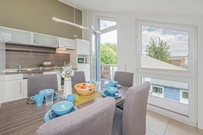 A modern kitchen with a dining area, large windows, and a view of the outside.