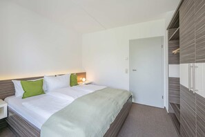 A hotel room with a bed, bedside table, and a wardrobe.