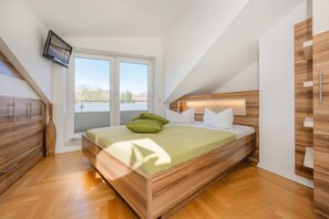 Un dormitorio moderno con cama, cabecero de madera y televisor montado en la pared.