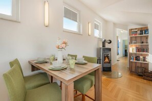Un comedor con una mesa preparada para cuatro personas, una chimenea y una estantería.