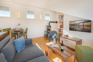 Una sala de estar moderna con un sofá, una mesa de comedor con sillas, una chimenea, una estantería y un ventanal con vistas.
