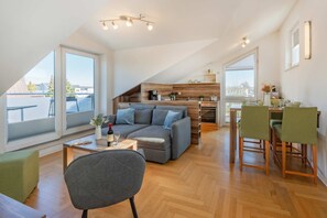 A modern loft apartment with a dining area, kitchen, and a large window overlooking a cityscape. - Apartment in Zinnowitz with balcony and WLAN - close to the beach on Usedom - House (Zinnowitz)