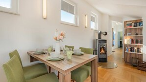 Un comedor con una mesa preparada para cuatro personas, una chimenea y una estantería.