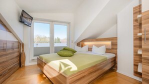 Un dormitorio moderno con cama, cabecero de madera y televisor montado en la pared.
