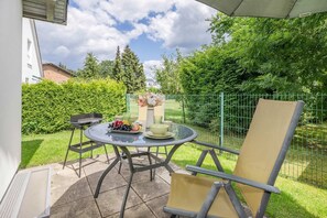A patio with a round table, chairs, and a grill.