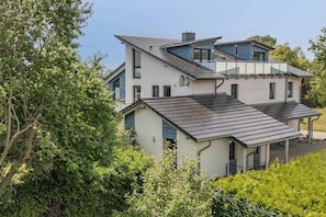 A two-story house with a sloped roof, a covered porch, and a visible chimney. - Cozy vacation apartment in Zinnowitz with a terrace and garden on Usedom - House (Zinnowitz)