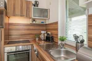 Una cocina moderna con armarios de madera, horno empotrado, cafetera, tostadora y ventana con vistas.