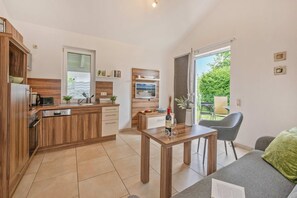 A compact kitchen with wooden cabinets, a built-in microwave, and a dining area with a table and chairs.