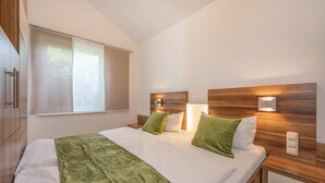 A hotel room with a bed, two bedside tables, a window, and a wall-mounted light fixture. - Cozy vacation apartment in Zinnowitz with terrace and garden on Usedom - House (Zinnowitz)