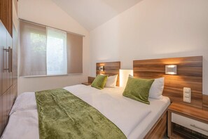 Ett hotellrum med en säng, två sängbord, ett fönster och en väggmonterad lampa.