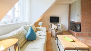 A cozy living room with a sofa, a television, a fireplace, and a window.