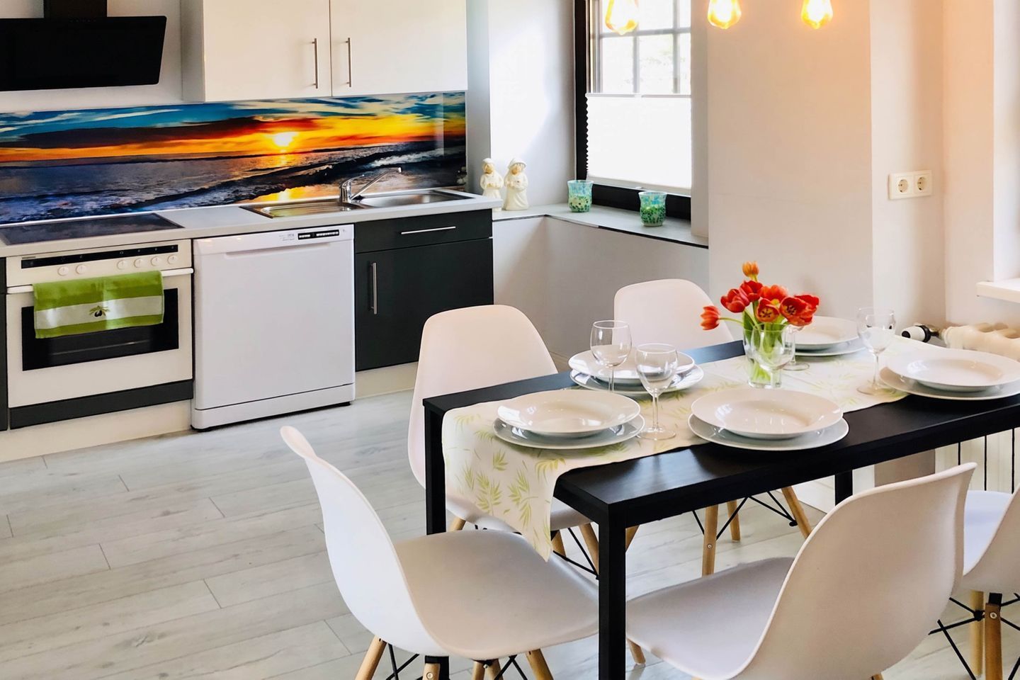 Cocina moderna con un ventanal grande, una mesa de comedor para cuatro y vistas a un atardecer.