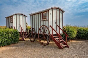 Two wooden structures with large wheels and stairs, surrounded by greenery. - Modern vacation apartment in Heringsdorf with terrace - 100 m to the beach - Us (Heringsdorf)