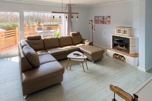 A modern living room with a sectional sofa, a coffee table, and a fireplace. - Modern vacation apartment in Heringsdorf with terrace - 100 m to the beach - Us (Heringsdorf)