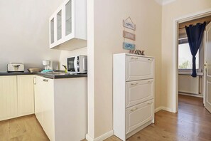 A kitchen with a microwave, toaster, and cabinets. There is a white refrigerator with drawers and a sign above it.