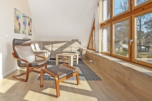 A modern living room with a sofa, two armchairs, a coffee table, and a wooden floor. - Modern vacation apartment in Heringsdorf with a terrace—100 m from the beach on Usedom (Heringsdorf)