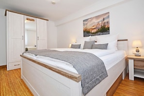 Une chambre à coucher avec un lit, une table de chevet, une lampe, une armoire et un tableau accroché au mur.