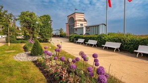 Ein Gebäude mit einer rosa Fassade, eine Fahnenstange mit Flaggen und eine Reihe von Bänken entlang eines Weges.