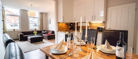 Una sala de estar moderna con un sofá, una mesa de comedor para cuatro personas y una cocina al fondo.