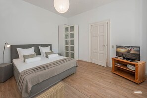 Ein Schlafzimmer mit Bett, Nachttisch, Lampe, Fernseher und einem Holztv-Schrank.