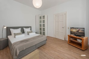 Ein Schlafzimmer mit Bett, Nachttisch, Lampe, Fernseher und einem Holztv-Schrank.