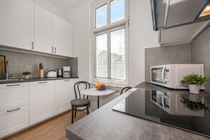 A modern kitchen with white cabinets, a black countertop, a dining table with chairs, and a microwave. - Charming vacation apartment in Heringsdorf, just 400 m from the beach - Villa (Heringsdorf)