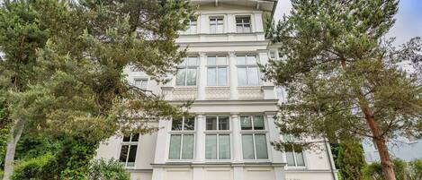A multi-story building with a symmetrical facade, large windows, and a central balcony.