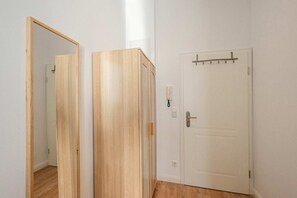 A room with a wooden door, a white wall, and a mirror reflecting part of the room.