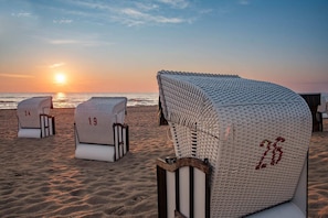 Des chaises de plage portant des numéros, un coucher de soleil en arrière-plan et une plage de sable.