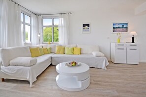Un salon moderne avec un canapé d’angle, une table basse ronde et un meuble blanc.