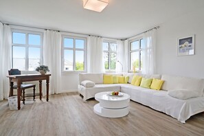 A modern living room with a white sofa, a round coffee table, and a dining table with chairs. - Spacious apartment in Heringsdorf with 2 bathrooms, just 300 m from the beach - (Heringsdorf)