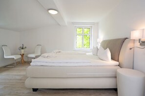Une chambre moderne avec un grand lit, une table de chevet, une chaise et une fenêtre.