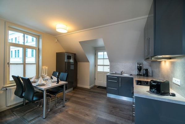 A modern kitchen with a dining area, featuring a built-in microwave, a coffee maker, and a toaster.