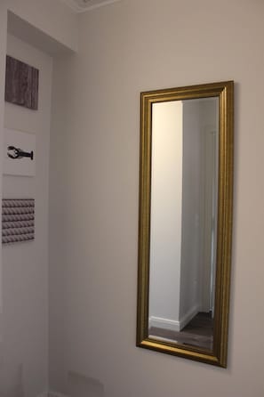 A mirror with a gold frame on a plain wall.
